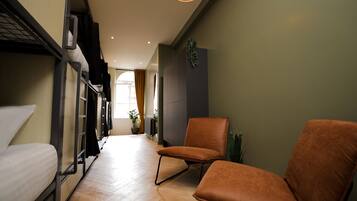 A narrow hallway with bunk beds on one side and two orange chairs on the other.