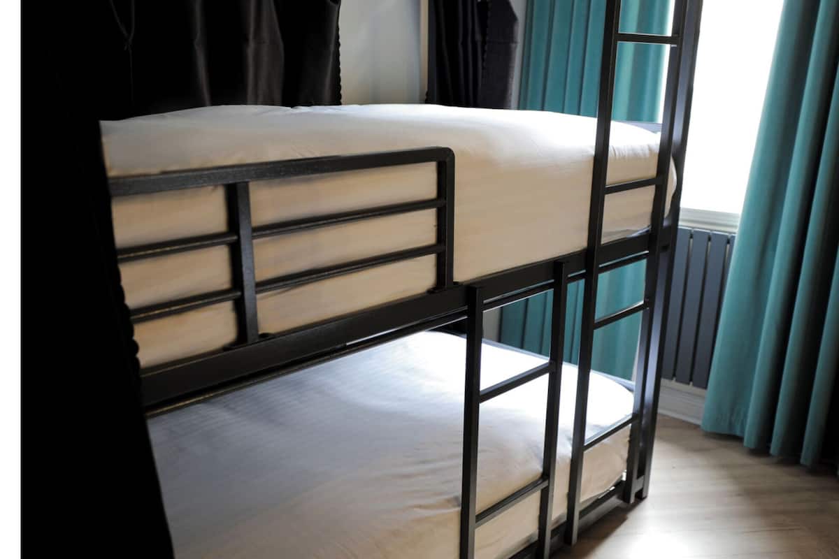 Ein Etagenbett mit schwarzem Gestell und beiger Bettwäsche.