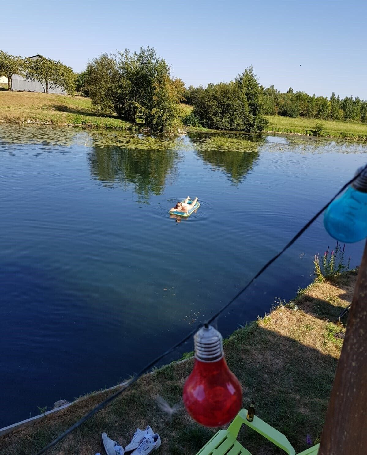 A calm lake with a person floating on a small inflatable raft.