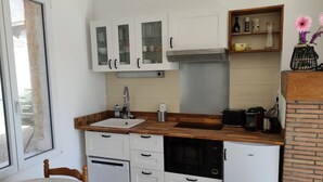 A compact kitchen with white cabinets, a built-in oven, a microwave, and a sink. - Relaxation on the banks of the Loir, Gîte2 (Les Roches L'Evêque)
