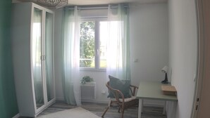 A small, bright room with a single window, a chair, a table, and a radiator. - Relaxation on the banks of the Loir, Gîte2 (Les Roches L'Evêque)