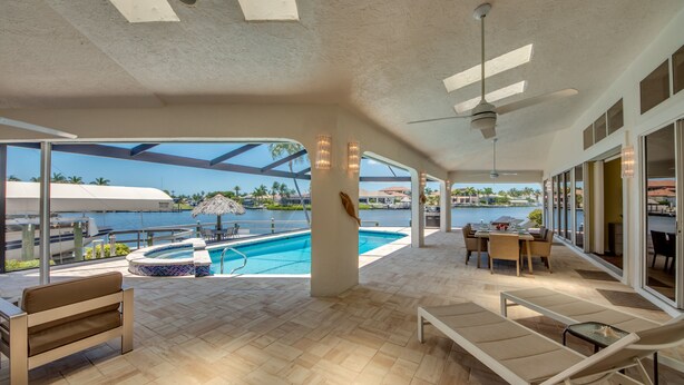 A spacious outdoor area with a pool, lounge chairs, and a table.