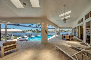Ampla área externa com piscina, espreguiçadeiras e mesa.