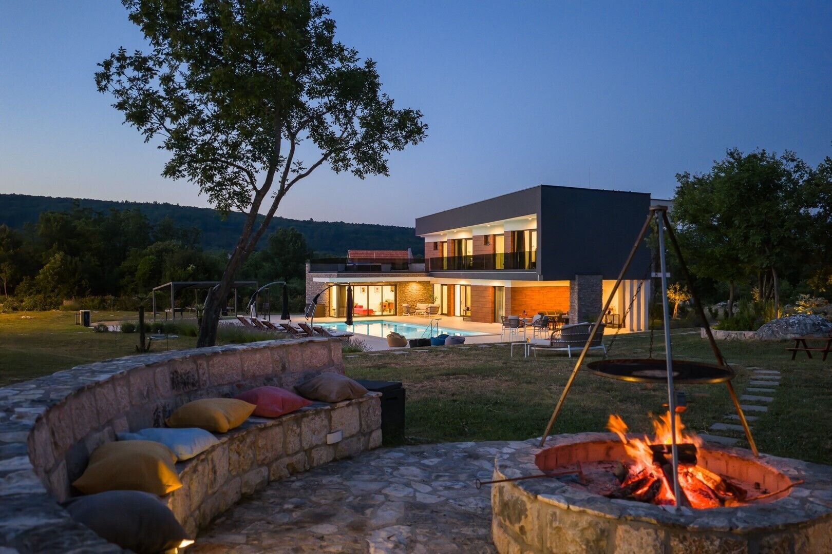 A modern house with a swimming pool, outdoor seating, and a fire pit.