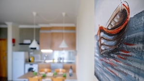 Une cuisine moderne avec un coin repas, un tableau au mur et une table à manger avec des chaises.