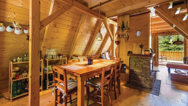 A wooden interior with a dining area, kitchen, and a view of the outdoors. - Beautiful 3-bed House in Crni Lug (Delnice)