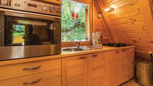 A kitchen with a stainless steel oven, a sink, wooden cabinets, and a window with reindeer decorations. - Beautiful 3-bed House in Crni Lug (Delnice)