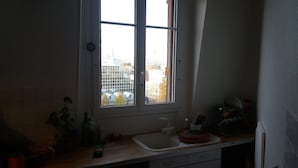 A kitchen with a window, a sink, and various kitchen items on the counter.