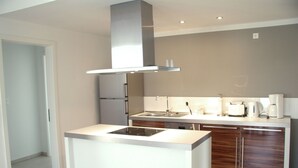 Een moderne keuken met een centraal kookeiland, roestvrijstalen apparatuur en een inbouwoven.