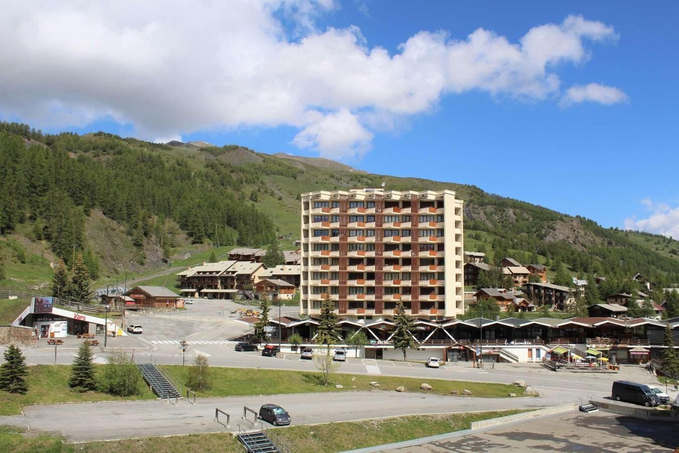 A multi-story hotel with a central atrium, surrounded by smaller buildings and a mountainous backdrop.