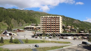 Un hotel de varios pisos con un atrio central, rodeado de edificios más pequeños y un paisaje montañoso de fondo.