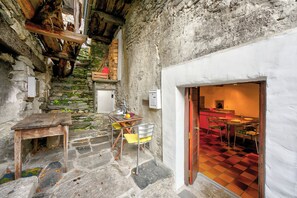 Una rústica escalera de piedra que conduce a un comedor con piso a cuadros y una mesa de madera con sillas.