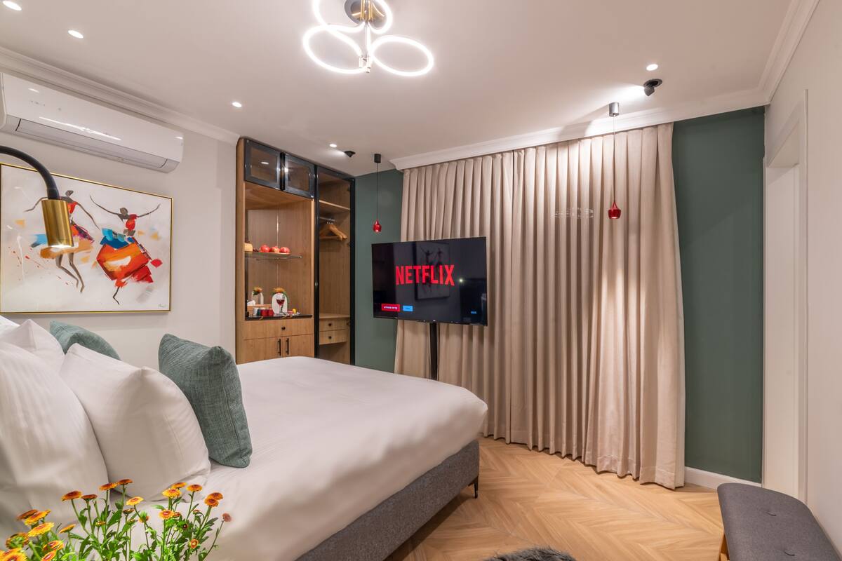 A modern hotel room with a large bed, a flat-screen TV, a wardrobe, and a desk.