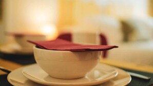 A white bowl with a red napkin on a saucer, placed on a table with a blurred background.