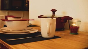 A kitchen counter with a microwave, a white mug, a glass with a candle, and a red pot.