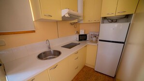 Cocina compacta con lavamanos, microondas y refrigerador.