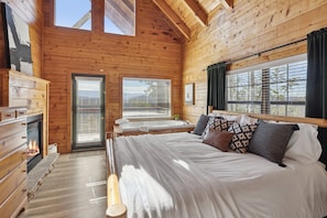 Cozy bedroom with a large bed, fireplace, and a window with blinds.