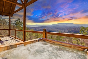 Relax in a hot tub on a deck overlooking the mountains.