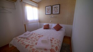 Ein ordentlich gemachtes Bett mit blumigem Bettzeug, zwei Kissen und gefalteten Handtüchern.