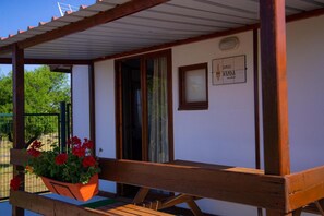 Una estructura de madera con un porche cubierto, una ventana y una placa con texto.