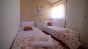 A room with two beds, each with a floral bedspread and a white pillow. There is a small cabinet between the beds, and a framed picture on the wall above the left bed. - Las Casitas de Guadamur.(Domus Wamba) (Guadamur)