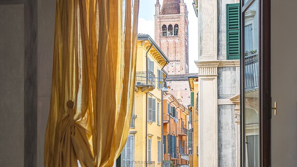 A room with a balcony, a view of a historic building, and a chair. - Billie's Flat RED - art & design apt in Verona historic centre (Verona)