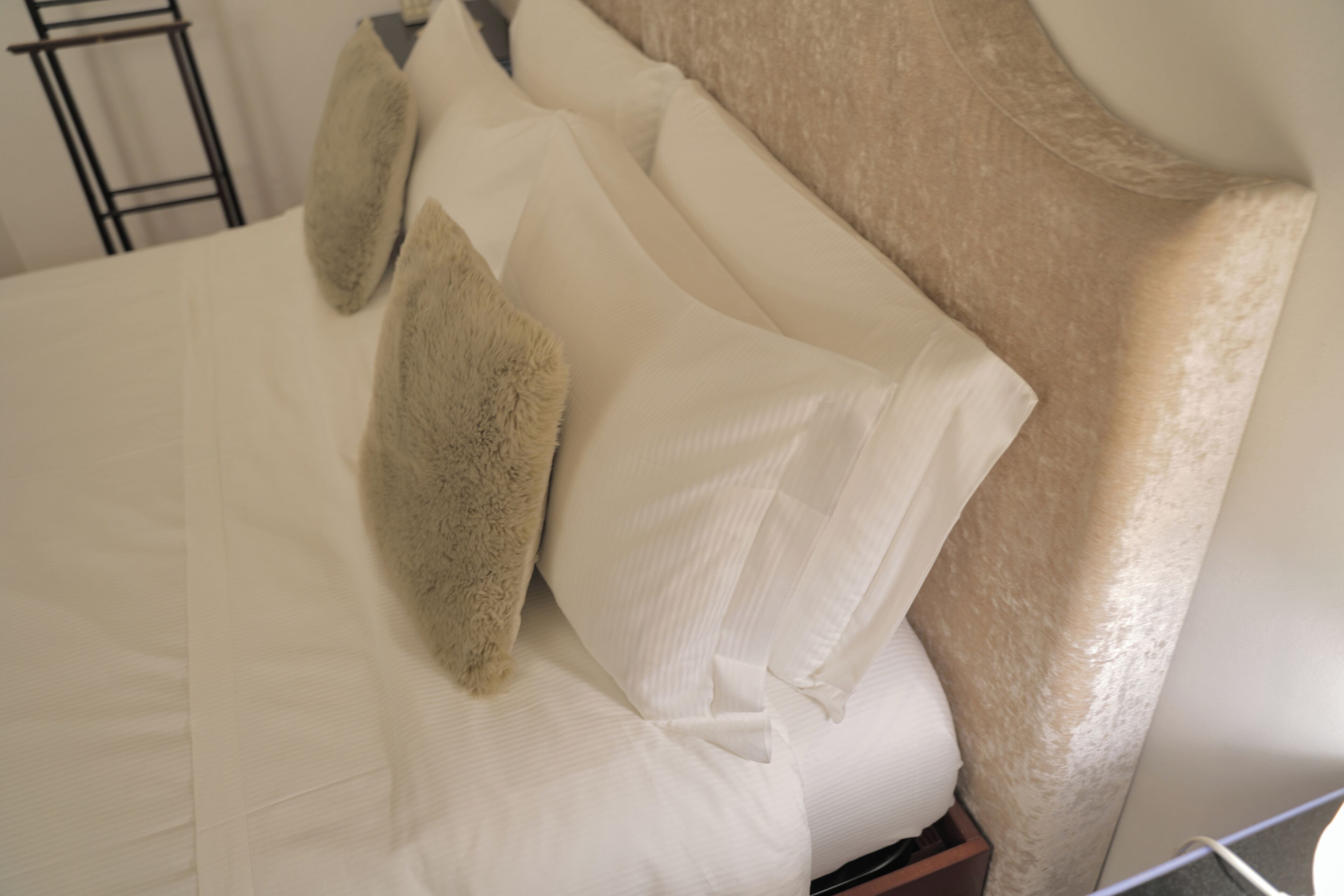Een bed met witte lakens en een zacht kussen.