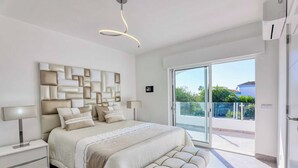 Ein modernes Schlafzimmer mit einem großen Bett, einer Bank, einem Nachttisch und einer an der Wand montierten Leuchte.