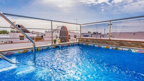 Une piscine sur le toit offrant une vue dégagée sur les toits de la ville et un bâtiment remarquable en arrière-plan.