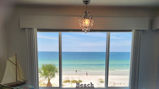 A room with a large window overlooking a beach, a sailboat model, and a chandelier. - LIVE ON THE BEACH. Gulf Beach Front - Spectacular views. (Indian Shores)