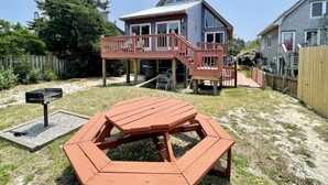 Een tweelaags huis met een terras en een picknicktafel in de achtertuin.