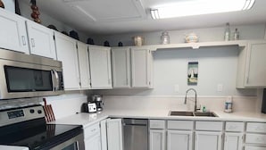 A modern kitchen with white cabinets, stainless steel appliances, and a tiled backsplash.