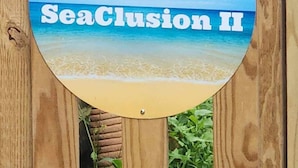 A wooden sign with a beach scene and the text "SeaClusion II" on it.
