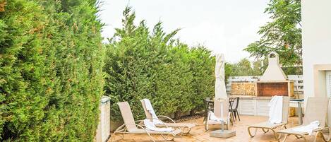 A poolside area with lounge chairs, a barbecue grill, and a brick patio.