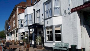 Eine traditionelle Kneipe namens 'The White Lion' mit klassischem Äußeren, einem Außenbereich zum Sitzen und einem kleinen Garten.