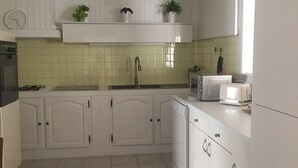 Una cocina con armarios blancos, salpicadero de azulejos, un fregadero, una estufa y un tostador.