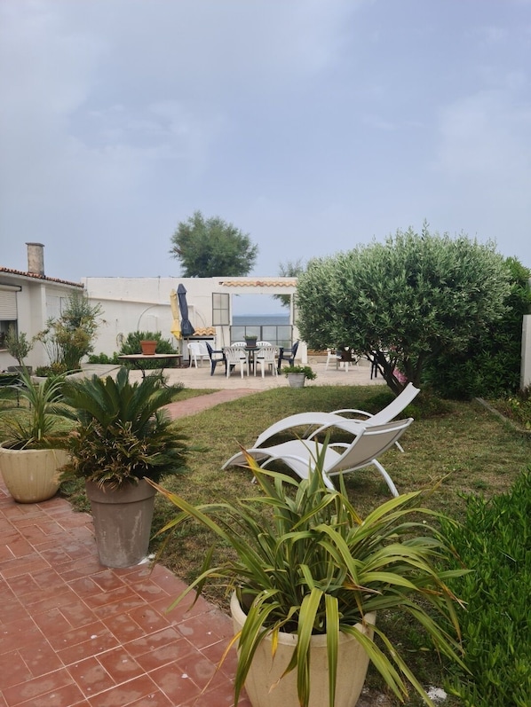 A patio area with outdoor seating, potted plants, and a view of the sea.