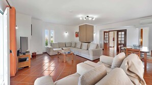 Un amplio salón con un conjunto de sofás, un televisor y una mesa de comedor.