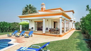 Una casa con piscina, mobiliario exterior y un porche cubierto.