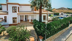 Una casa de varios pisos con piscina, un patio cubierto y vistas del paisaje circundante.