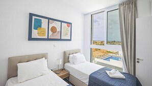 A hotel room with two beds, a large window with a view of a pool and landscape, and a wall-mounted artwork. - Vie Bleu 15 - Three Bedroom Villa, Sleeps 6 (Πρωταράς)