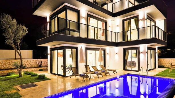 A modern multi-story house with a swimming pool, outdoor seating, and a well-lit exterior. - Villa Tanyeli 1 - Three Bedroom Villa, Sleeps 6 (Kalkan)