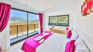 A modern bedroom with a large bed, a view of the outdoors, and a wooden deck outside the window. - Villa Tanyeli 1 - Three Bedroom Villa, Sleeps 6 (Kalkan)