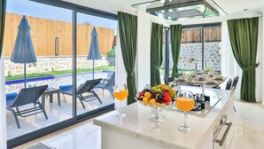 A modern kitchen with a marble countertop, a fruit bowl, and two glasses of orange juice. - Villa Tanyeli 1 - Three Bedroom Villa, Sleeps 6 (Kalkan)