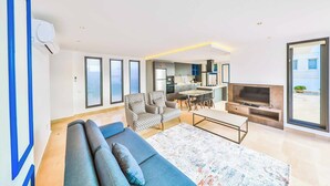 A modern living room with a sofa, a TV, and a dining area. - Villa Marni - Six Bedroom Villa, Sleeps 12 (Kalkan)