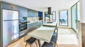 A modern kitchen with a central island, stainless steel appliances, and a large sliding glass door leading to a balcony. - Villa Marni - Six Bedroom Villa, Sleeps 12 (Kalkan)