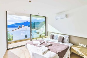 A modern bedroom with a large bed, a bedside table, and a view of a mountainous landscape through a large window.