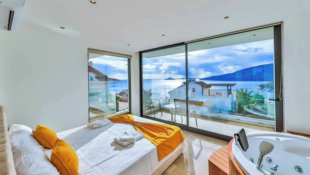 A modern hotel room with a bed, a large window, and a bathroom with a bathtub. - Villa Marni - Six Bedroom Villa, Sleeps 12 (Kalkan)