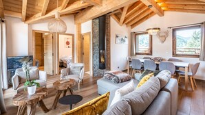 A spacious living area with wooden beams, a stone fireplace, and a dining area with a view of the outdoors.