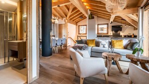 A spacious loft with exposed wooden beams, a modern kitchen, and a cozy seating area with a sofa and chairs.